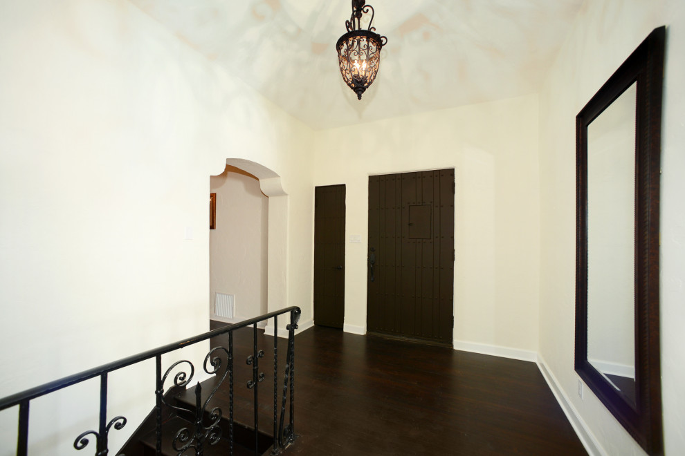 Photo of a medium sized traditional foyer in Los Angeles with white walls, dark hardwood flooring, a single front door, a brown front door, brown floors, a vaulted ceiling and feature lighting.