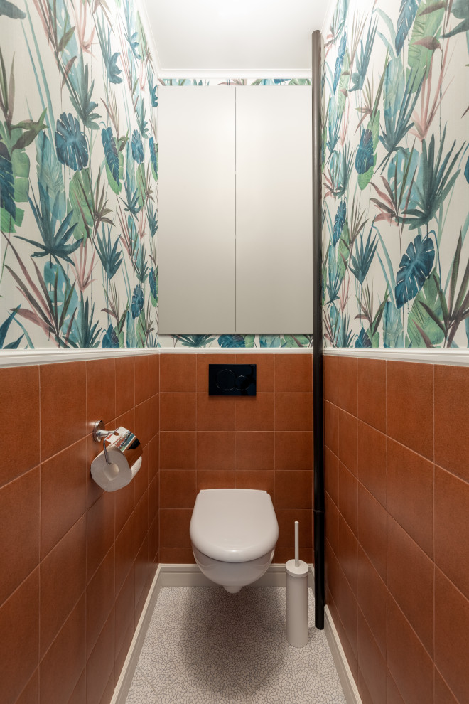 Idéer för ett litet nordiskt toalett, med släta luckor, beige skåp, en vägghängd toalettstol, orange kakel, keramikplattor, flerfärgade väggar, klinkergolv i keramik och grått golv
