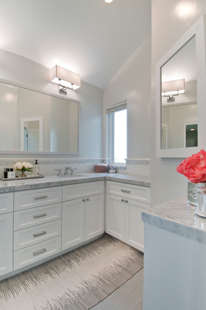This is an example of a mid-sized transitional master bathroom in Los Angeles with recessed-panel cabinets, white cabinets, an alcove tub, a shower/bathtub combo, a two-piece toilet, white tile, subway tile, grey walls, porcelain floors, an undermount sink and marble benchtops.