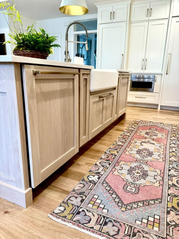 Example of a mid-sized transitional l-shaped light wood floor, brown floor and wallpaper ceiling eat-in kitchen design in Atlanta with a farmhouse sink, shaker cabinets, white cabinets, granite countertops, white backsplash, stainless steel appliances, an island and white countertops