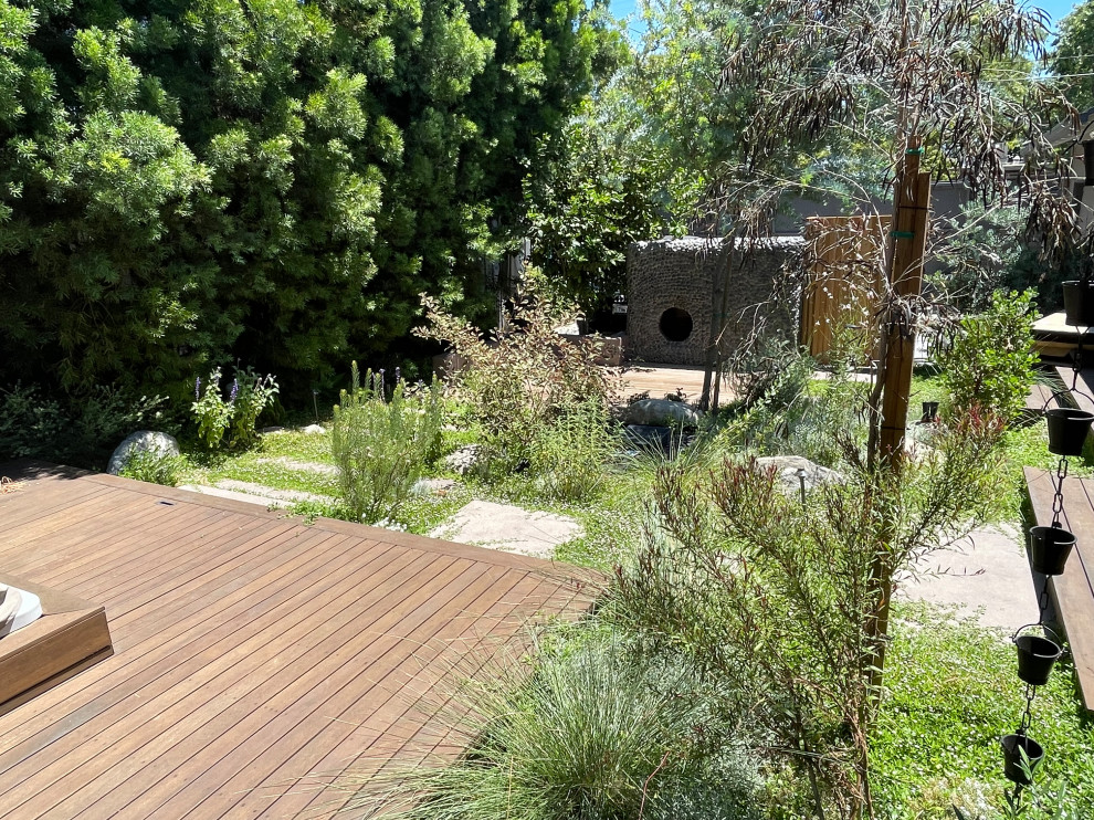 Photo of a mid-sized eclectic backyard full sun xeriscape for spring in Los Angeles with with privacy feature, decking and a wood fence.
