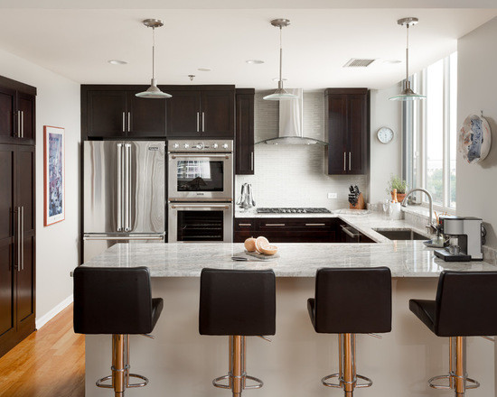 Mid-sized transitional u-shaped medium tone wood floor open concept kitchen photo in Chicago with an undermount sink, shaker cabinets, dark wood cabinets, marble countertops, white backsplash, subway tile backsplash, stainless steel appliances and a peninsula