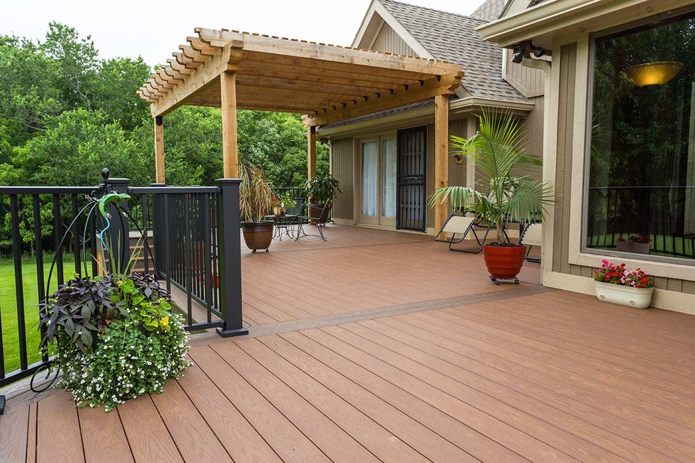 This is an example of a large traditional backyard deck in Kansas City with a container garden and a pergola.