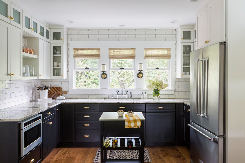 This is an example of a mid-sized transitional u-shaped kitchen in Los Angeles with an undermount sink, shaker cabinets, white splashback, subway tile splashback, stainless steel appliances, medium hardwood floors, with island, brown floor and white cabinets.