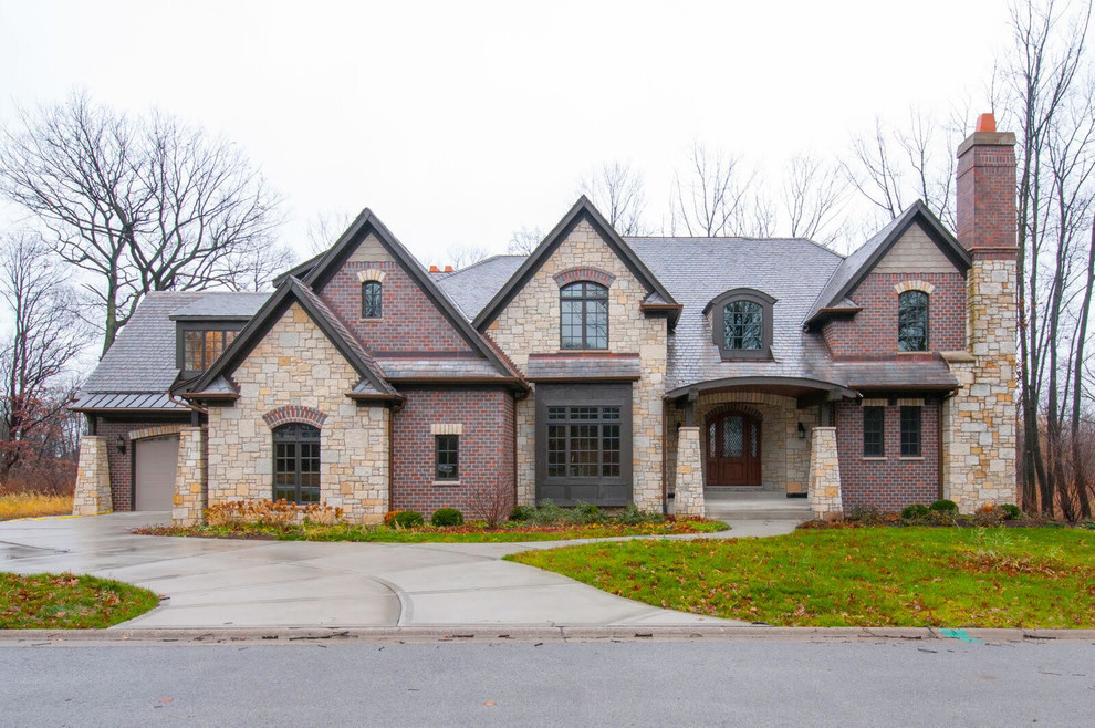This is an example of an expansive transitional two-storey brick red house exterior in Chicago with a hip roof and a shingle roof.