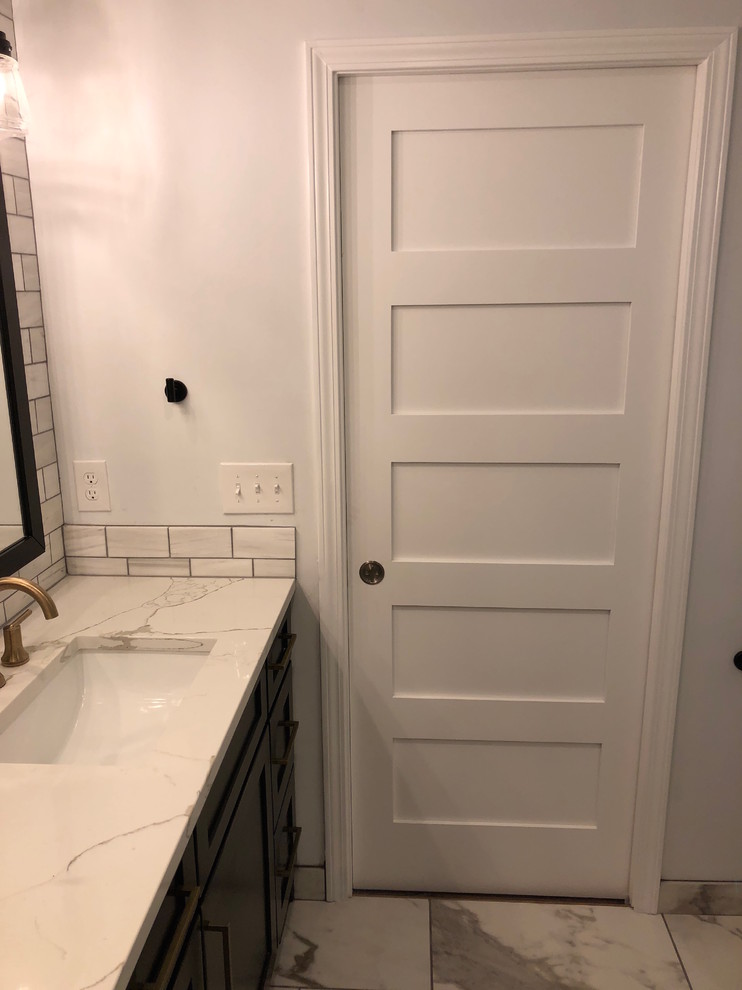 Inspiration for a mid-sized transitional master gray tile and marble tile porcelain tile and gray floor corner shower remodel with recessed-panel cabinets, distressed cabinets, a one-piece toilet, gray walls, an undermount sink, quartz countertops, a hinged shower door and gray countertops