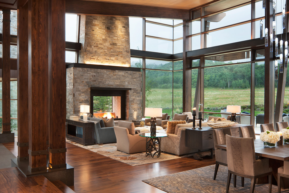 This is an example of a country living room in Denver with medium hardwood floors, a two-sided fireplace, a stone fireplace surround and brown floor.