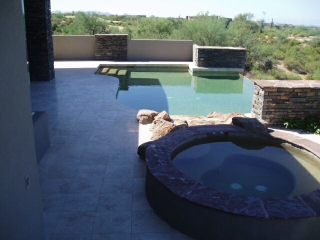Example of a small backyard tile and custom-shaped infinity hot tub design in Phoenix
