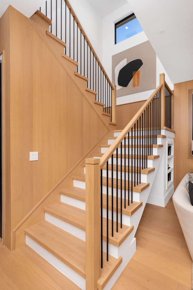 Photo of a large transitional wood u-shaped staircase in Los Angeles with wood railing and wood walls.