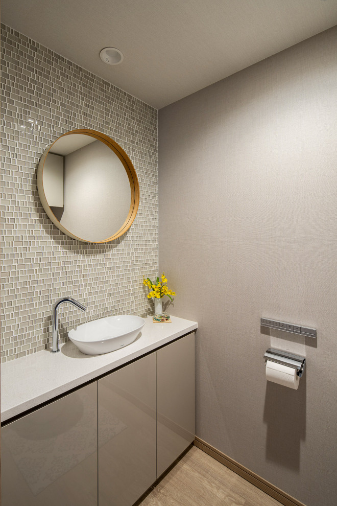Пример оригинального дизайна: туалет среднего размера в скандинавском стиле с белыми фасадами, бежевой плиткой, стеклянной плиткой, белой столешницей и встроенной тумбой