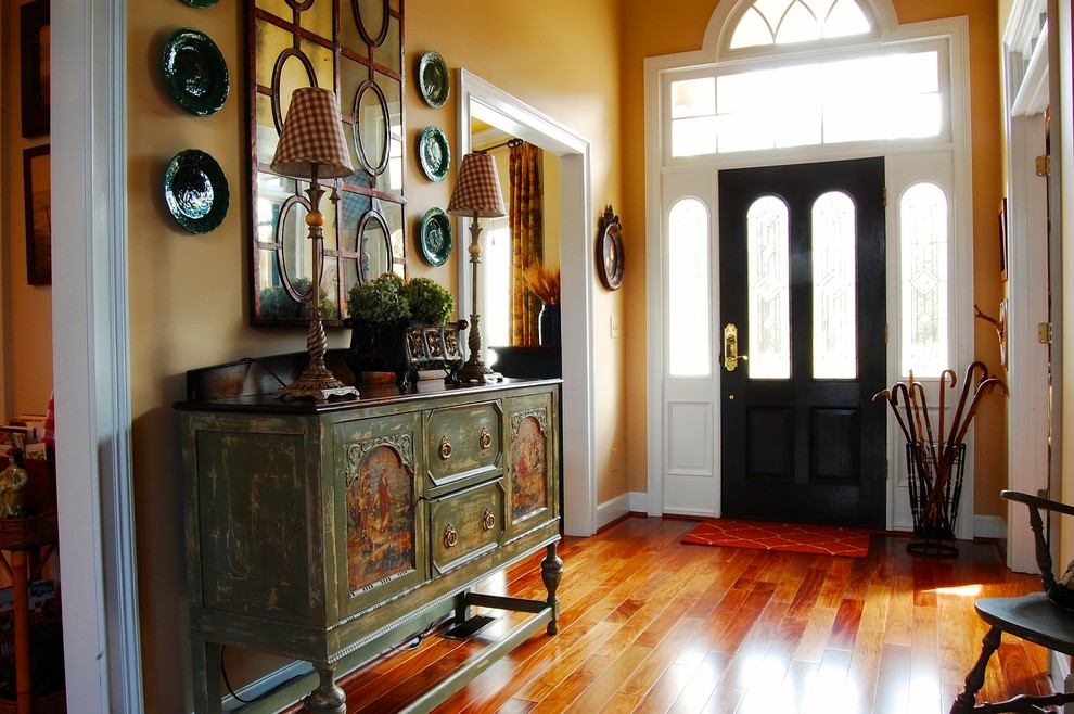 Inspiration for a foyer in New York with yellow walls, medium hardwood floors, a single front door and a black front door.