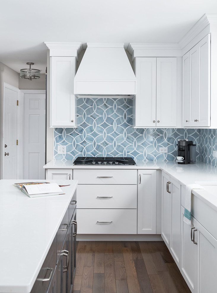 Mid-sized transitional u-shaped eat-in kitchen in Chicago with an undermount sink, recessed-panel cabinets, white cabinets, quartz benchtops, blue splashback, ceramic splashback, stainless steel appliances, dark hardwood floors, with island, brown floor and white benchtop.