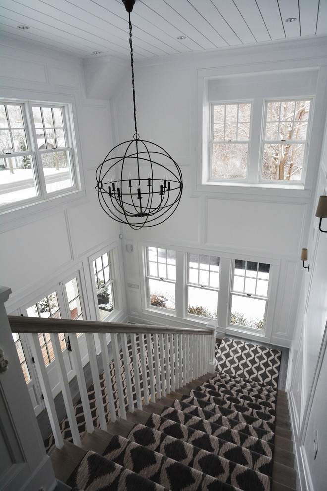 This is an example of an expansive country foyer in New York with white walls, painted wood floors, a single front door and a white front door.