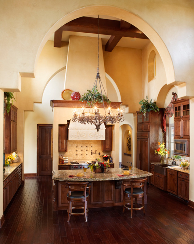 Inspiration for an expansive mediterranean u-shaped eat-in kitchen in Austin with a drop-in sink, dark wood cabinets, granite benchtops, stainless steel appliances, dark hardwood floors and with island.