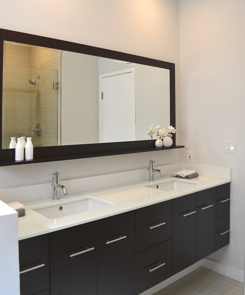 Photo of a small modern master bathroom in Los Angeles with an undermount sink, flat-panel cabinets, solid surface benchtops, a drop-in tub, an alcove shower, a one-piece toilet, beige tile, porcelain tile, white walls, porcelain floors and dark wood cabinets.