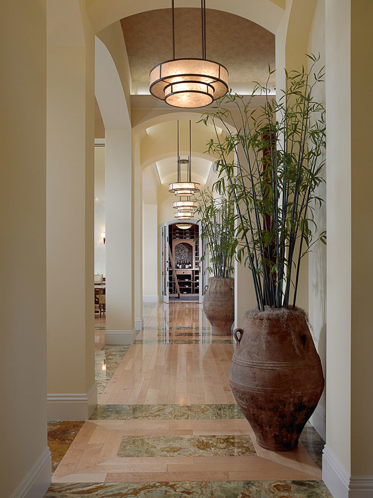 Inspiration for an expansive mediterranean hallway in Miami with beige walls and light hardwood floors.