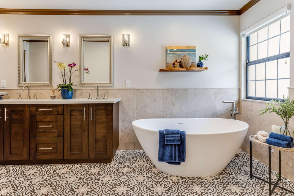 Design ideas for a mediterranean master bathroom in San Francisco with shaker cabinets, brown cabinets, a freestanding tub, beige tile, an undermount sink, multi-coloured floor, a double vanity and a built-in vanity.