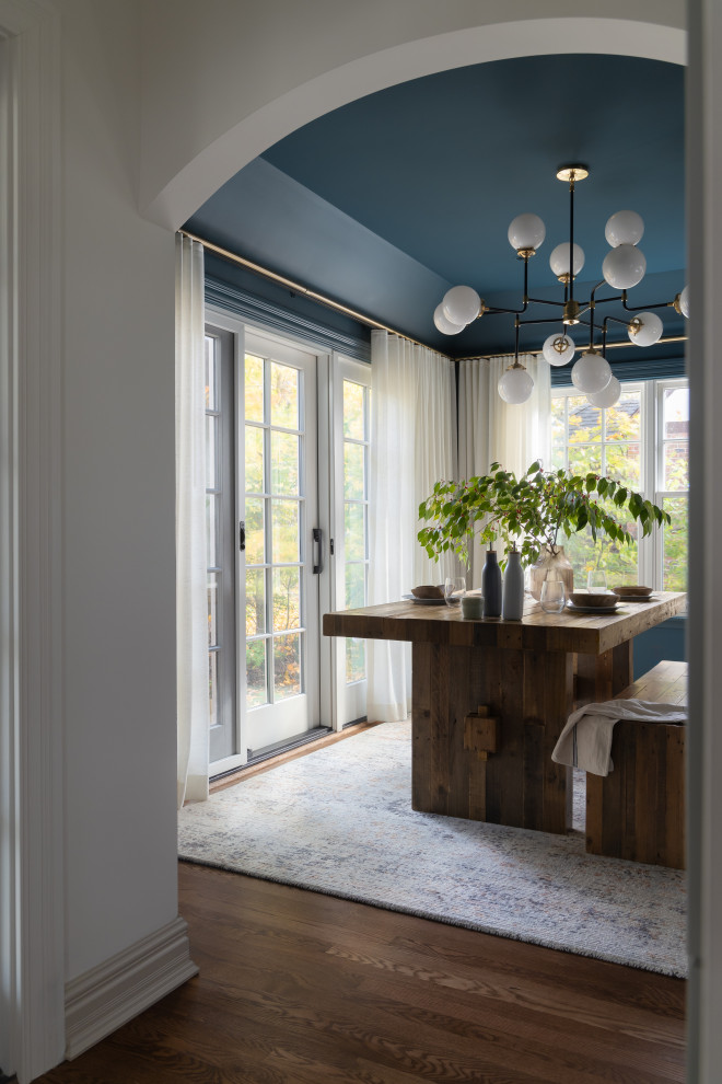 Immagine di una sala da pranzo minimalista di medie dimensioni e chiusa con pareti blu e pavimento in legno massello medio