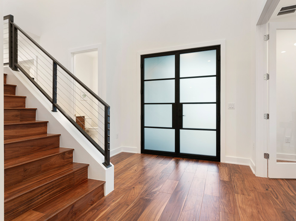 Cette photo montre une entrée moderne de taille moyenne avec parquet clair, une porte double, une porte noire et un sol marron.