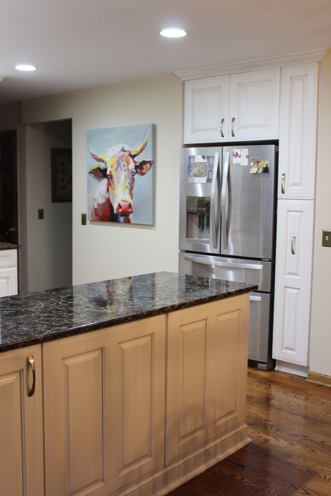 This is an example of a mid-sized transitional l-shaped eat-in kitchen in Detroit with a double-bowl sink, raised-panel cabinets, white cabinets, quartz benchtops, beige splashback, glass tile splashback, stainless steel appliances, medium hardwood floors, a peninsula, brown floor and brown benchtop.