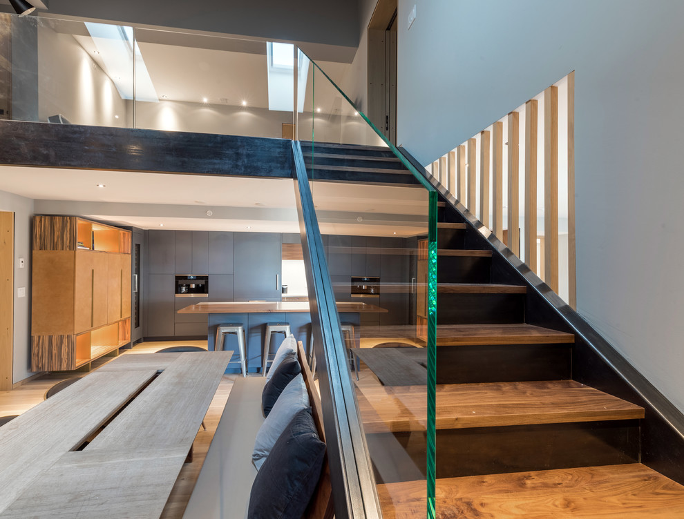 Modern Stairway with a Glass Railing - A modern straight run stairway with a seamless glass railing and dark to light wood risers and treads. It's a sophisticated staircase for this modern house! 

Built by ULFBUILT. Putting together the details to build dream homes is our specialty. This is done through attention to detail, execution, and a focus on our client’s wants and needs. Contact us today to learn more.