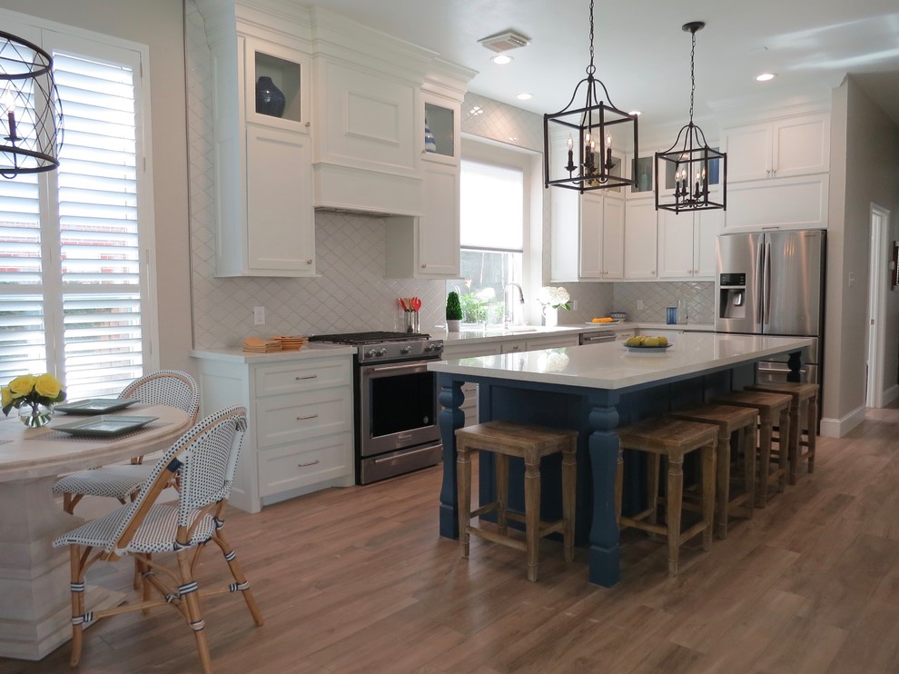 Photo of a mid-sized transitional l-shaped kitchen in Houston with an undermount sink, shaker cabinets, white cabinets, quartz benchtops, grey splashback, ceramic splashback, stainless steel appliances, porcelain floors, with island, brown floor and white benchtop.