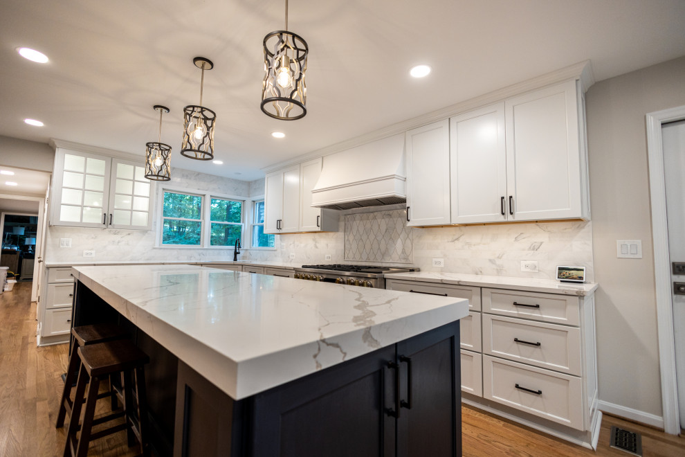 Inspiration for a large transitional l-shaped light wood floor and brown floor eat-in kitchen remodel in Baltimore with an undermount sink, shaker cabinets, white cabinets, quartz countertops, white backsplash, marble backsplash, stainless steel appliances, an island and white countertops