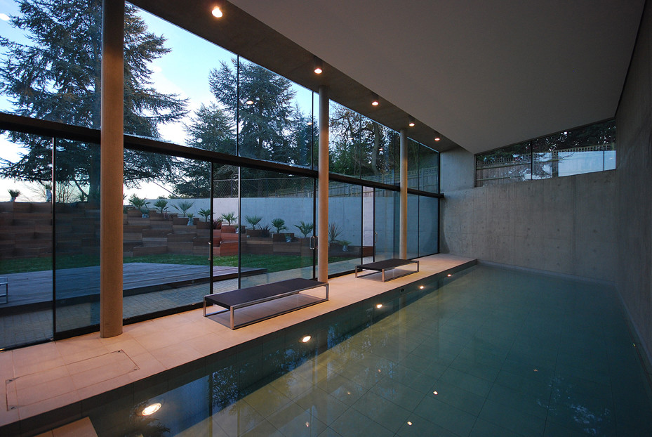 Photo of a large contemporary indoor rectangular pool in London with a pool house and natural stone pavers.