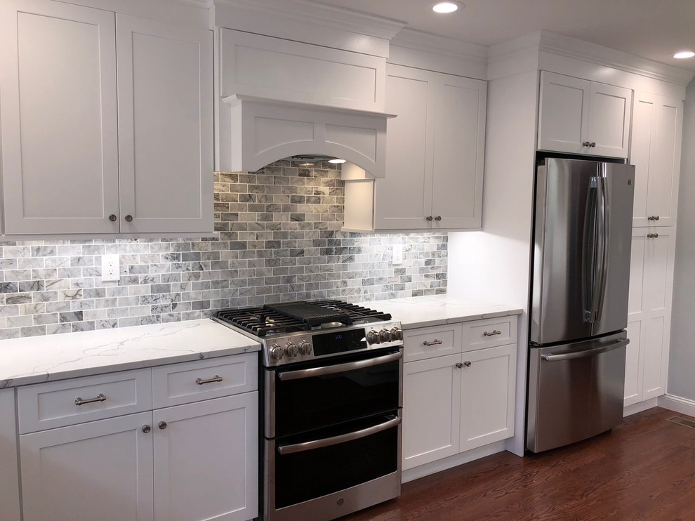 Enclosed kitchen - mid-sized transitional u-shaped dark wood floor and brown floor enclosed kitchen idea with an undermount sink, shaker cabinets, white cabinets, marble countertops, gray backsplash, stone tile backsplash, stainless steel appliances, no island and white countertops