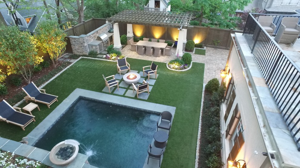 This is an example of a small transitional backyard patio in Atlanta with natural stone pavers, an outdoor kitchen and a pergola.