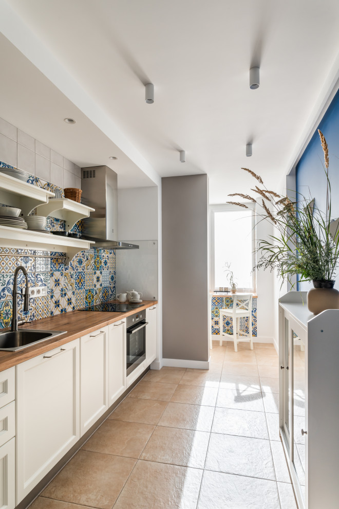 Inspiration for a mid-sized mediterranean single-wall separate kitchen in Other with a drop-in sink, recessed-panel cabinets, white cabinets, laminate benchtops, multi-coloured splashback, stone slab splashback, stainless steel appliances, porcelain floors, brown floor and brown benchtop.