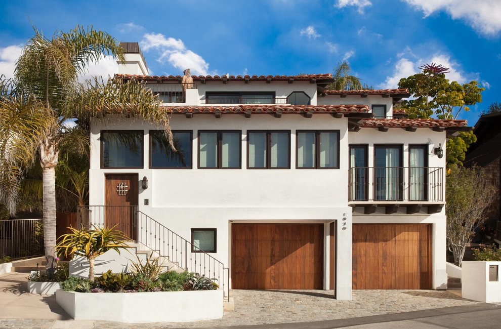 Inspiration for a large mediterranean three-storey adobe white house exterior in Orange County with a gable roof and a tile roof.