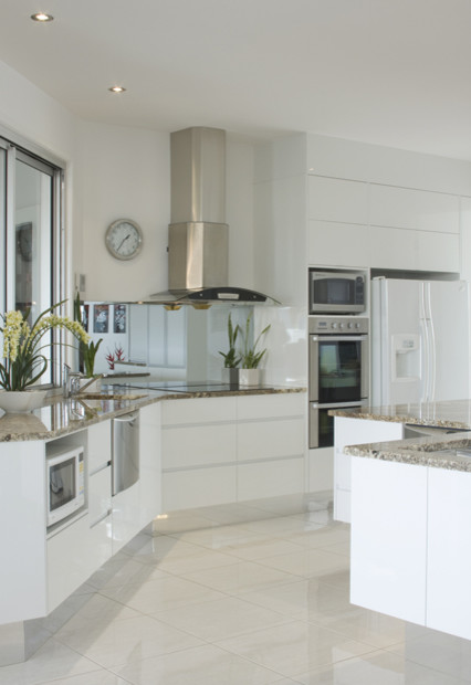 Inspiration for a large contemporary open plan kitchen in Sunshine Coast with a single-bowl sink, white cabinets, granite benchtops, glass sheet splashback, stainless steel appliances, porcelain floors and with island.