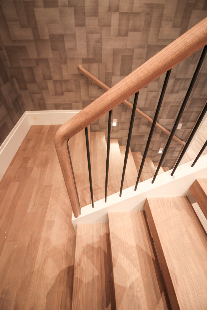 This is an example of a large modern wood u-shaped staircase in DC Metro with wood risers, metal railing and wallpaper.