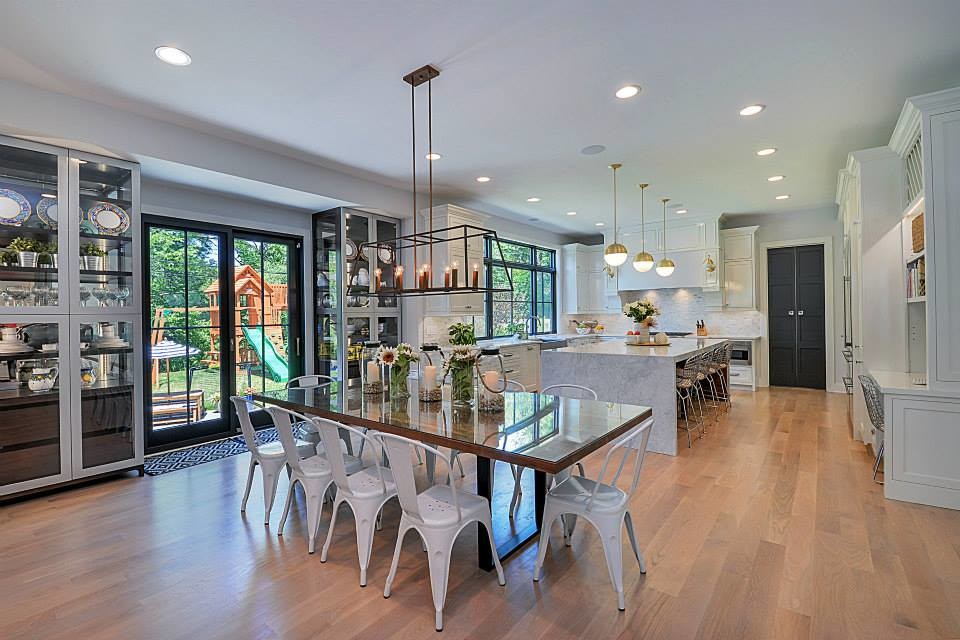 Mid-sized transitional u-shaped light wood floor and brown floor eat-in kitchen photo in Chicago with white cabinets, a farmhouse sink, recessed-panel cabinets, marble countertops, gray backsplash, mosaic tile backsplash, stainless steel appliances and an island
