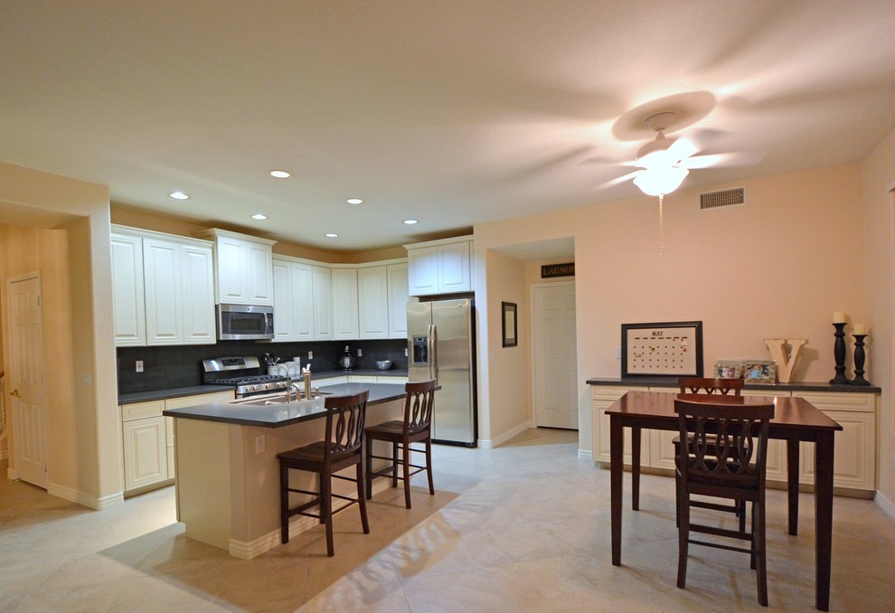Example of a mid-sized transitional l-shaped ceramic tile open concept kitchen design in Phoenix with shaker cabinets, white cabinets, gray backsplash, an island, a double-bowl sink, quartz countertops, stone slab backsplash and stainless steel appliances