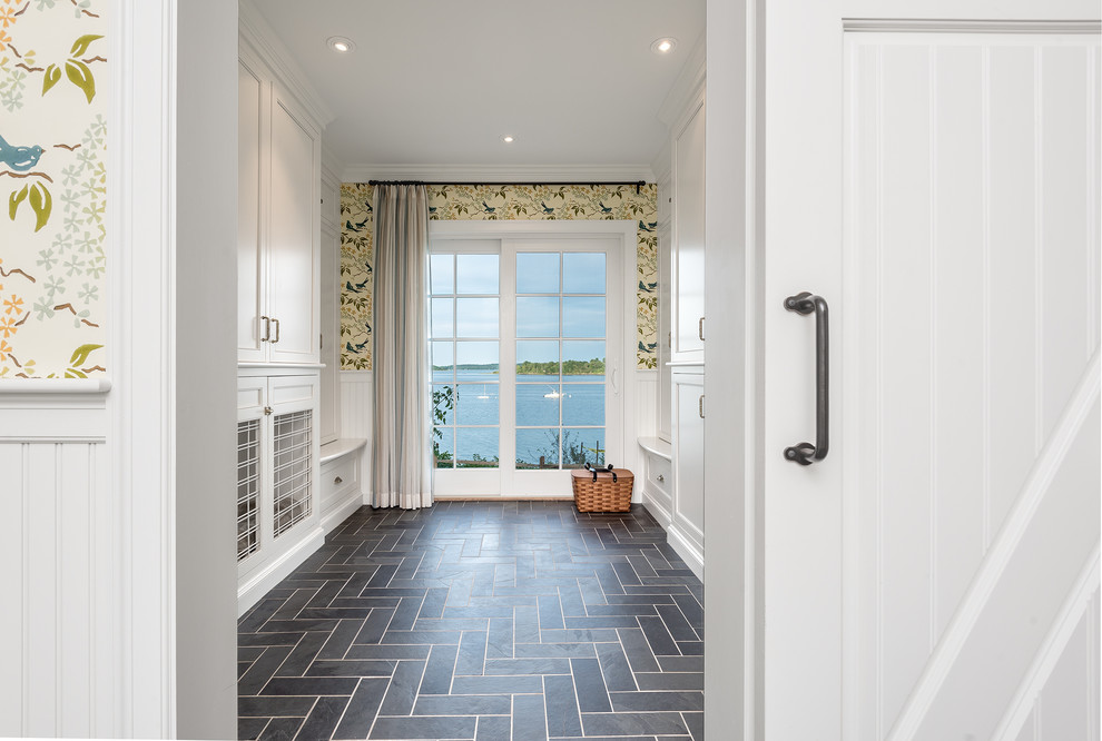 Photo of a large beach style dedicated laundry room in Portland Maine with white cabinets, multi-coloured walls, slate floors, black floor and recessed-panel cabinets.