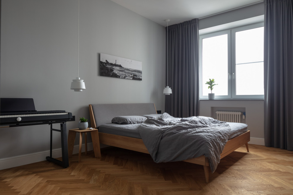 На фото: серо-белая спальня среднего размера в скандинавском стиле с серыми стенами, паркетным полом среднего тона и коричневым полом без камина