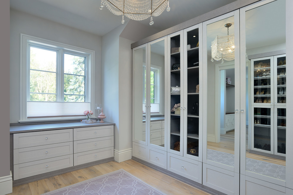 Design ideas for a mid-sized transitional women's walk-in wardrobe in Toronto with light hardwood floors, beige floor, shaker cabinets and white cabinets.