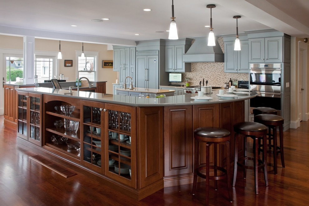 Large transitional u-shaped dark wood floor and brown floor eat-in kitchen photo with a farmhouse sink, quartz countertops, beige backsplash, porcelain backsplash, stainless steel appliances, two islands, raised-panel cabinets and blue cabinets