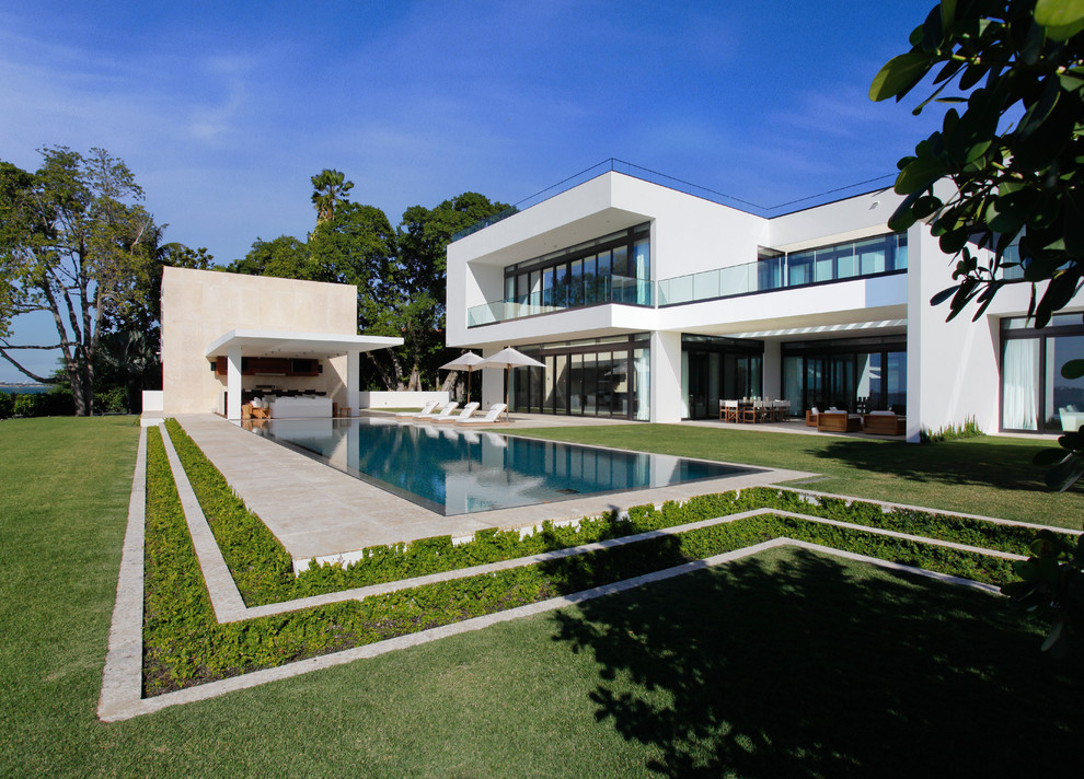 Large modern backyard rectangular infinity pool in Miami with tile.