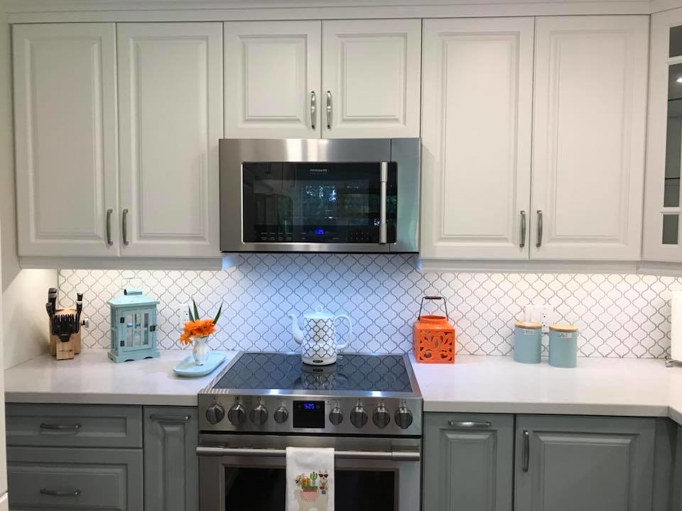 Eat-in kitchen - transitional u-shaped medium tone wood floor eat-in kitchen idea in Toronto with an undermount sink, raised-panel cabinets, white cabinets, quartz countertops, white backsplash, porcelain backsplash, stainless steel appliances, no island and white countertops