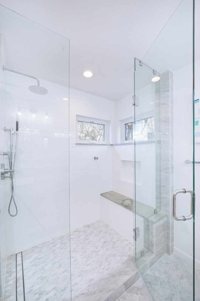 This is an example of a mid-sized transitional master bathroom in Denver with white cabinets, white tile, marble floors, a hinged shower door, recessed-panel cabinets, a corner shower, a one-piece toilet, marble, white walls, an undermount sink, limestone benchtops, white floor and grey benchtops.