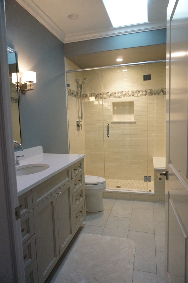 Photo of a small transitional kids bathroom in Chicago with an undermount sink, recessed-panel cabinets, beige cabinets, engineered quartz benchtops, an alcove shower, a one-piece toilet, beige tile, porcelain tile, blue walls and porcelain floors.