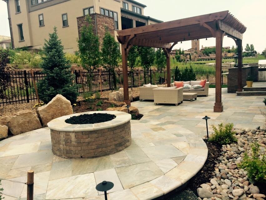 Design ideas for a mid-sized traditional backyard patio in Denver with a fire feature, natural stone pavers and a pergola.