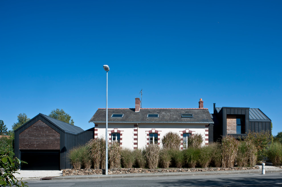 Réalisation d'une grande façade de maison noire design en bois et bardage à clin à un étage avec un toit à deux pans, un toit en métal et un toit noir.
