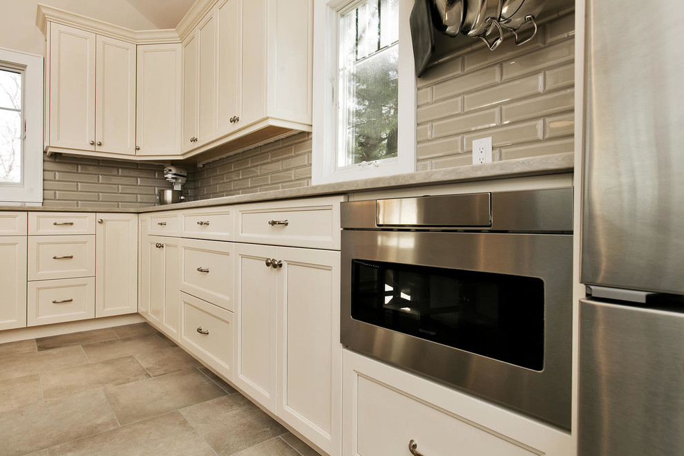 Eat-in kitchen - mid-sized transitional u-shaped porcelain tile eat-in kitchen idea in New York with an undermount sink, recessed-panel cabinets, white cabinets, wood countertops, gray backsplash, subway tile backsplash, stainless steel appliances and an island