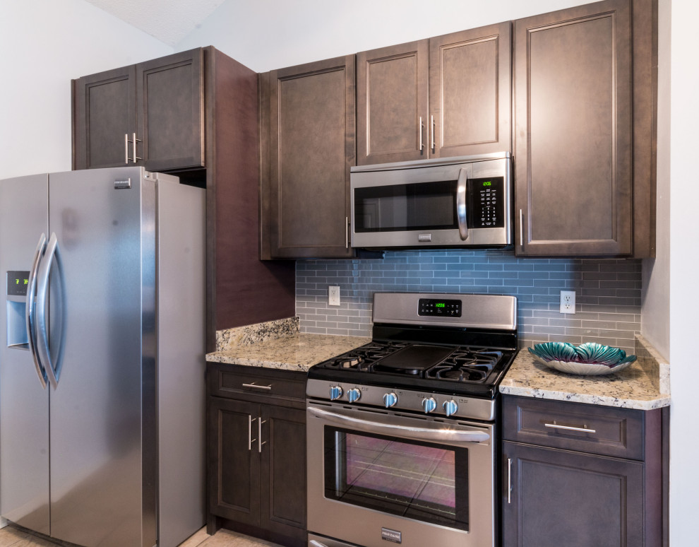 Small galley cement tile floor and beige floor eat-in kitchen photo with an undermount sink, flat-panel cabinets, gray cabinets, granite countertops, gray backsplash, glass tile backsplash, stainless steel appliances, no island and white countertops