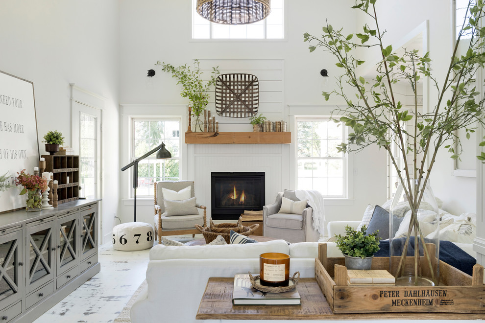 Photo of a mid-sized country open concept living room in Minneapolis with white walls, painted wood floors, a wood fireplace surround, white floor and a standard fireplace.