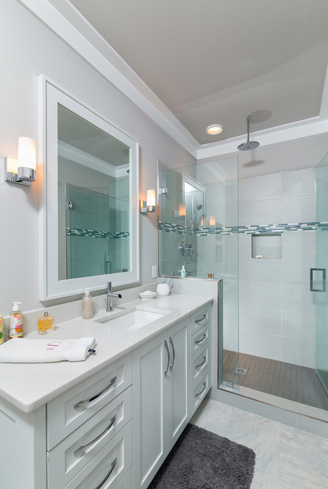 Mid-sized beach style 3/4 bathroom in Atlanta with an undermount sink, shaker cabinets, white cabinets, solid surface benchtops, an alcove shower, a one-piece toilet, white tile, porcelain tile, white walls and porcelain floors.